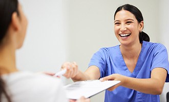 Front desk offering financing forms with a smile