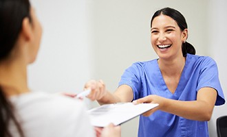 Woman smiling while handing patient form