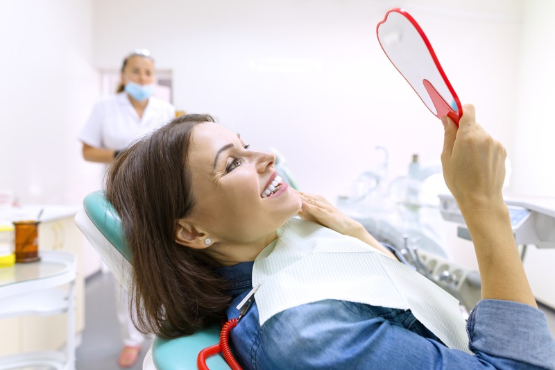 Patient smiling in the mirror with dental implant restorations